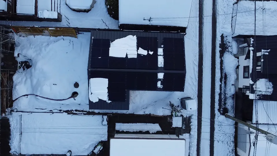 Aerial view of black solar panels on a snow covered roof in Metro Vancouver