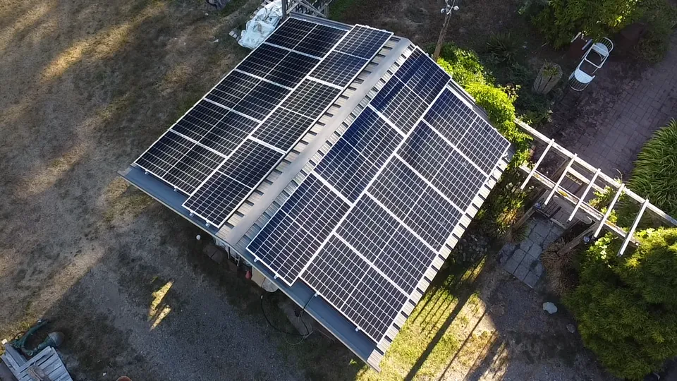 Drone view of a residential solar array on a sloped roof beside a garden
