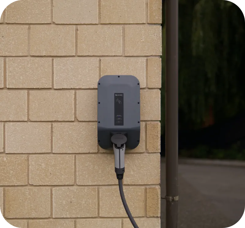 A wall mounted EV charger installed on the exterior brick wall of a home
