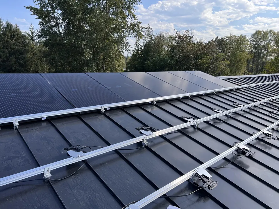 Microinverters mounted on racking under solar panels on a standing seam metal roof