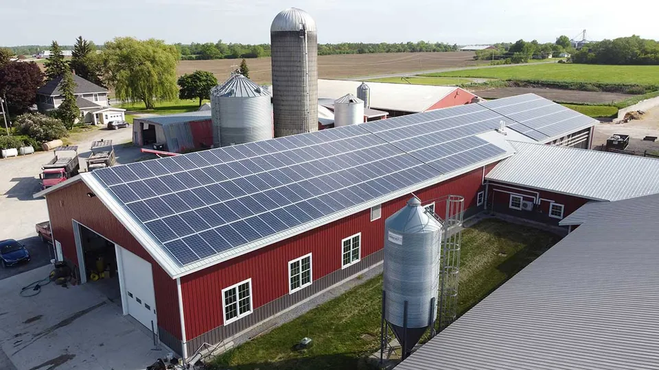 Solar array on the roof of a red farm building beside grain silos in the Fraser Valley