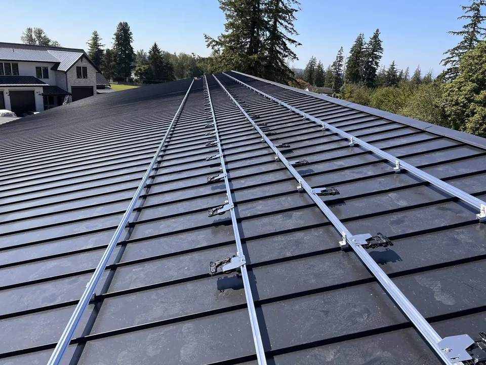 Solar racking rails and footings installed across a standing seam metal roof before the panels go on